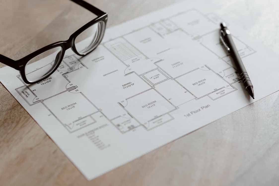 Floor plan, glasses and pen on a desk while planning interior painting costs for an Auckland home